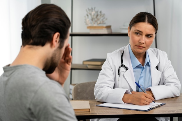 Homem de vista lateral falando com o médico