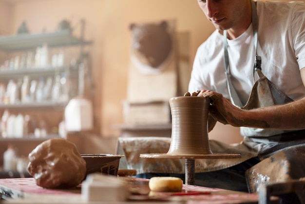 Homem de vista lateral fazendo cerâmica dentro de casa