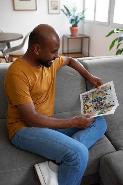 Homem de vista lateral lendo quadrinhos em casa
