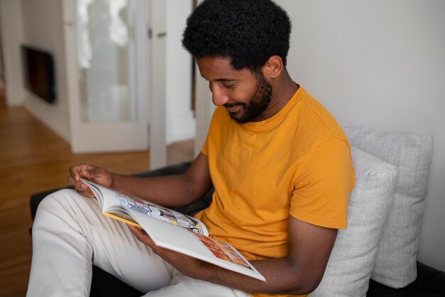 Homem de vista lateral lendo quadrinhos em casa