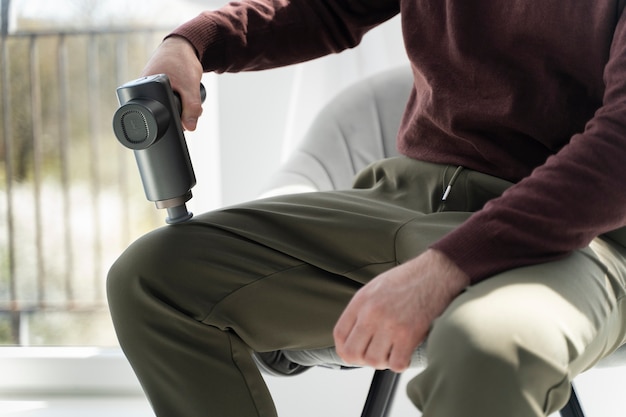 Homem de vista lateral usando pistola de massagem