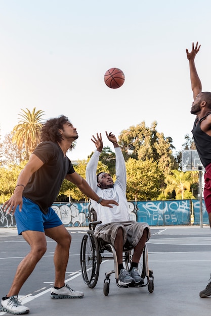 Foto grátis homem deficiente em cadeira de rodas jogando basquete com outras pessoas