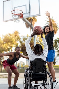 Homem deficiente em cadeira de rodas jogando basquete com outras pessoas