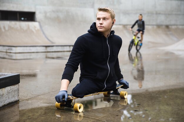 Homem deficiente jovem e motivado com um longboard em um skatepark