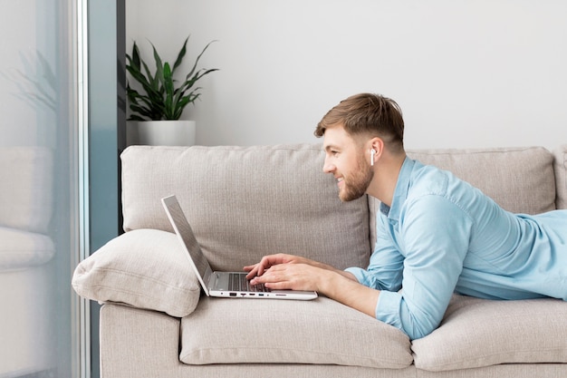 Foto grátis homem deitado no sofá com o laptop