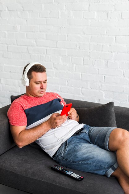 Homem deitado no sofá, ouvindo música no fone de ouvido