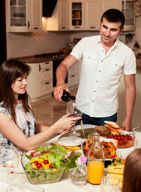 Homem derramando um copo de vinho para mulher na mesa de jantar