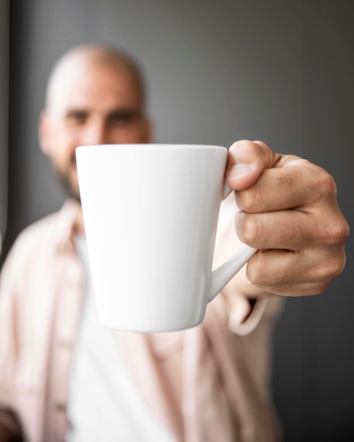 Homem desfocado segurando uma caneca