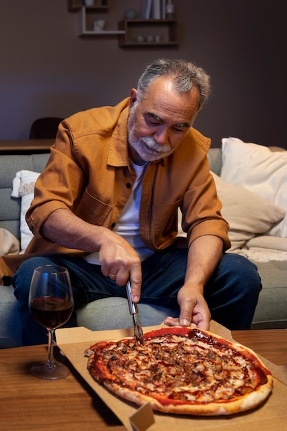 Homem desfrutando de uma pizza enquanto está sozinho em casa