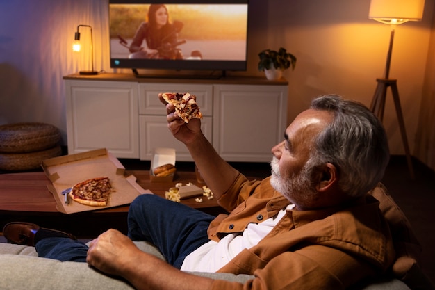 Homem desfrutando de uma pizza enquanto está sozinho em casa