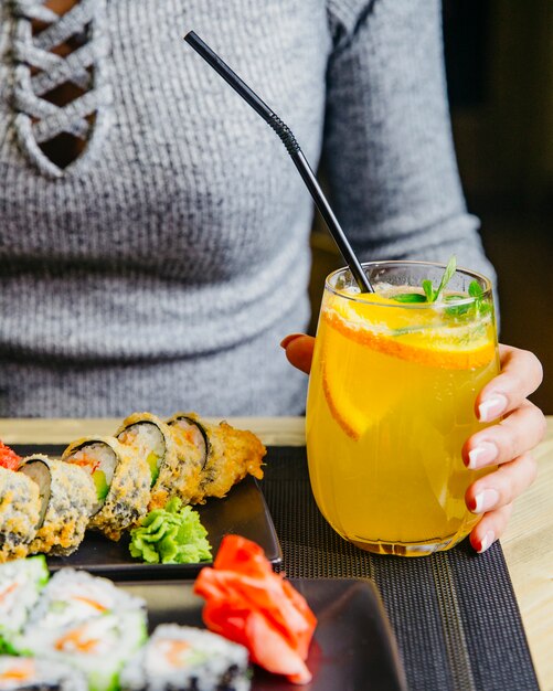 Homem detém vidro com vista lateral para a água com gás de menta laranja cocktail cítrico