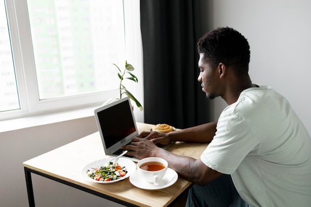 Foto grátis homem digitando no laptop em casa tiro médio