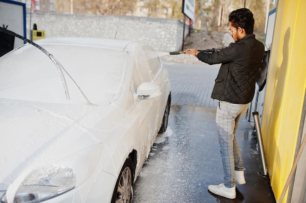 Homem do sul da Ásia ou homem indiano lavando seu transporte branco na lavagem de carros