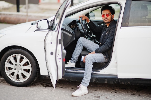 Homem do sul da Ásia ou homem indiano usa óculos vermelhos sentados dentro de seu carro de transporte branco