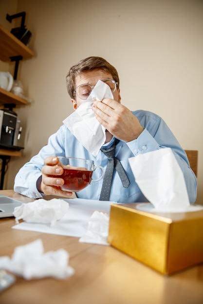 Homem doente enquanto trabalhava no escritório, sofrendo de gripe sazonal.