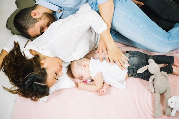 Homem dormindo abraçando esposa e bebê