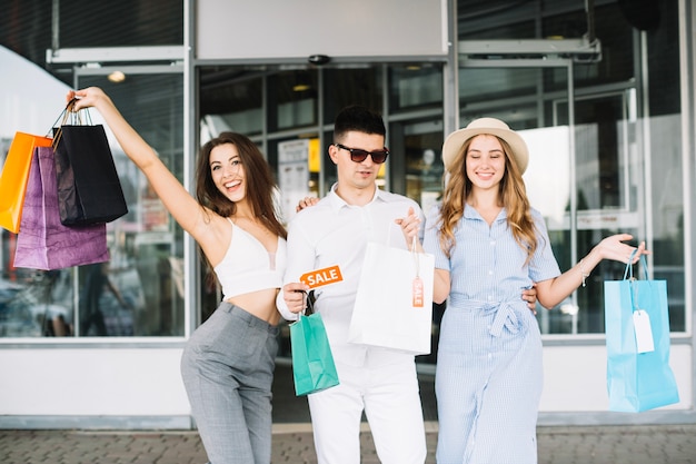 Homem e duas mulheres com sacos de papel