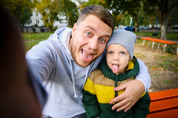 Homem e menino tirando uma selfie com as línguas