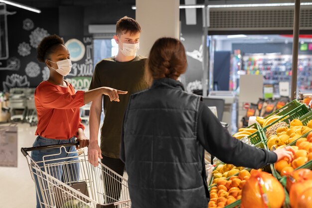 Homem e mulher com máscaras médicas fazendo compras com carrinho de compras