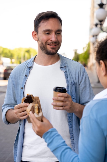 Foto grátis homem e mulher curtindo comida para viagem na rua