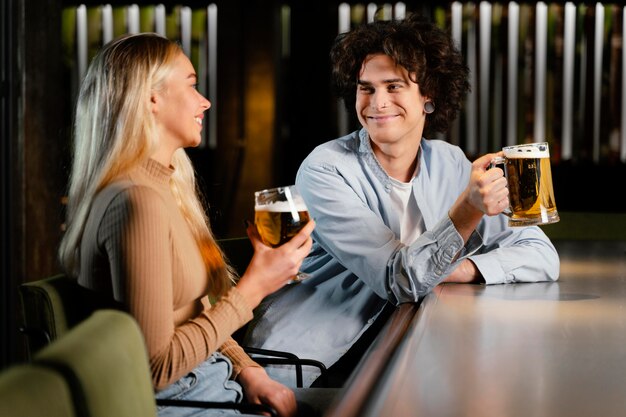 Homem e mulher de tiro médio com canecas de cerveja