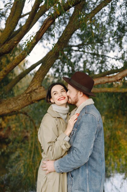 Homem e mulher em roupas da moda, descansando juntos na natureza perto do lago