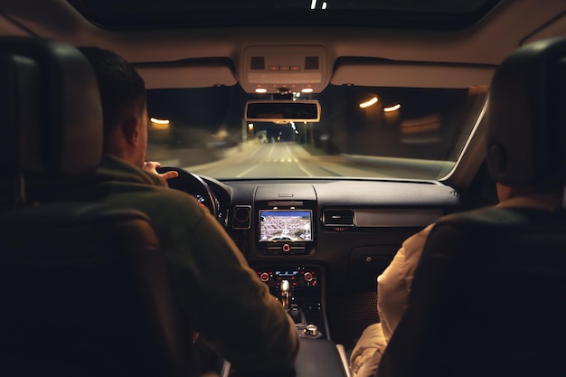 Homem e mulher em um carro à noite vista do carro