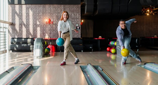 Homem e mulher jogando bolas de boliche no beco