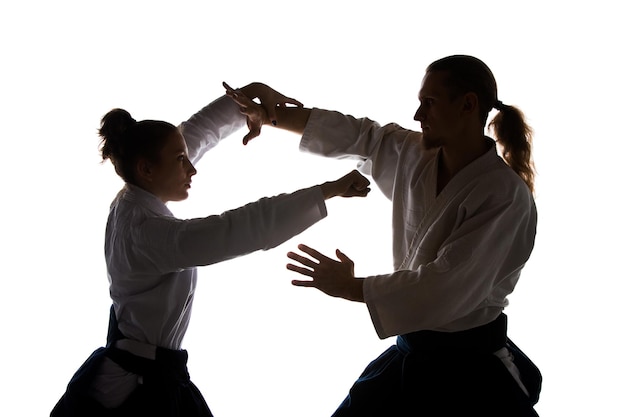 Homem e mulher lutando e treinando aikido na parede branca do estúdio