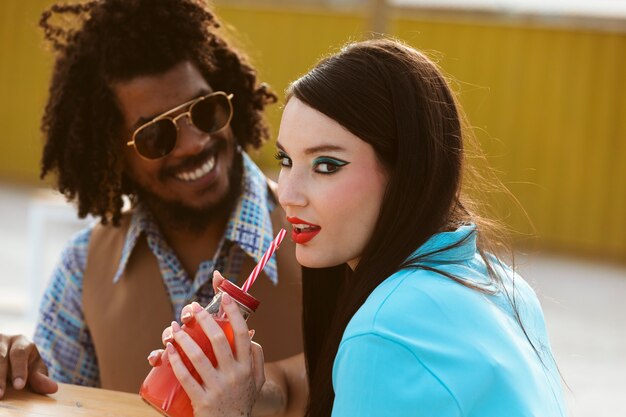 Homem e mulher posando juntos em estilo retrô com bebida