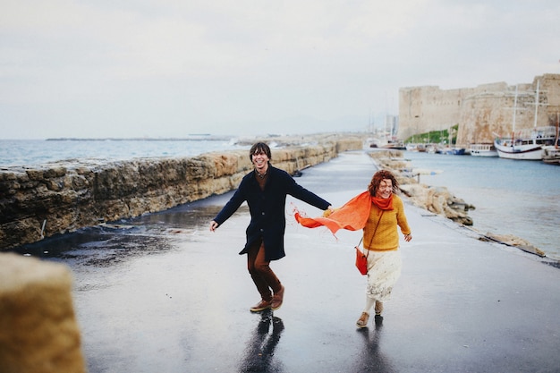 Homem e mulher se divertem na chuva, costa vazia