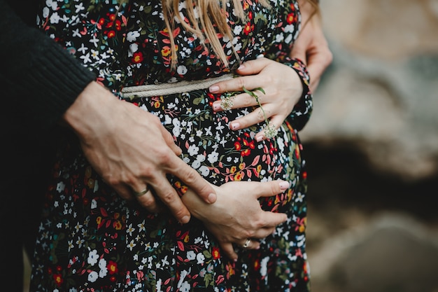 Homem e mulher segurar suas mãos na barriga de grávida. por família