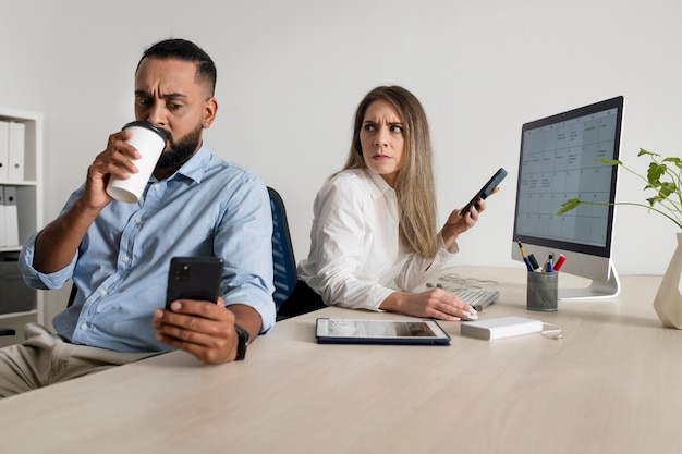 Homem e mulher sendo viciados em seus telefones, mesmo no trabalho