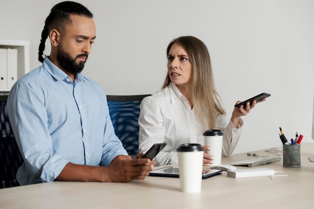 Homem e mulher sendo viciados em seus telefones, mesmo no trabalho