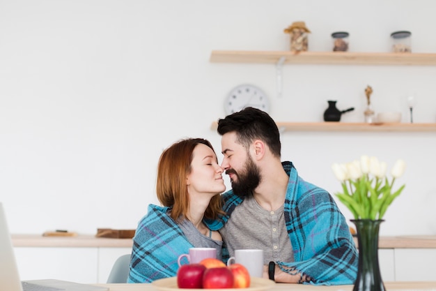 Homem e mulher sentada na cozinha com um cobertor