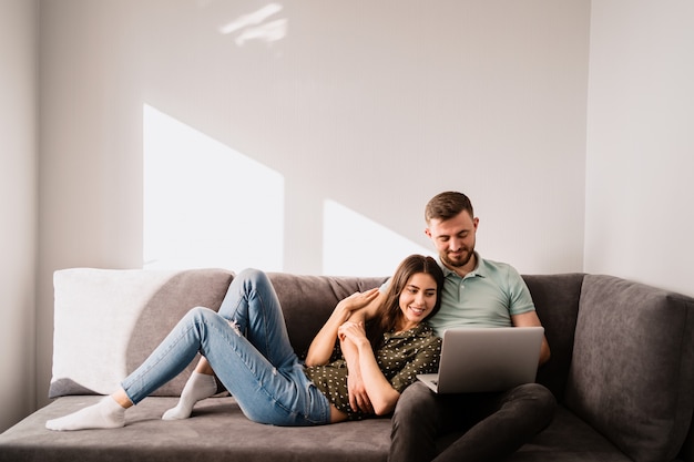 Homem e mulher sentada no sofá com um laptop