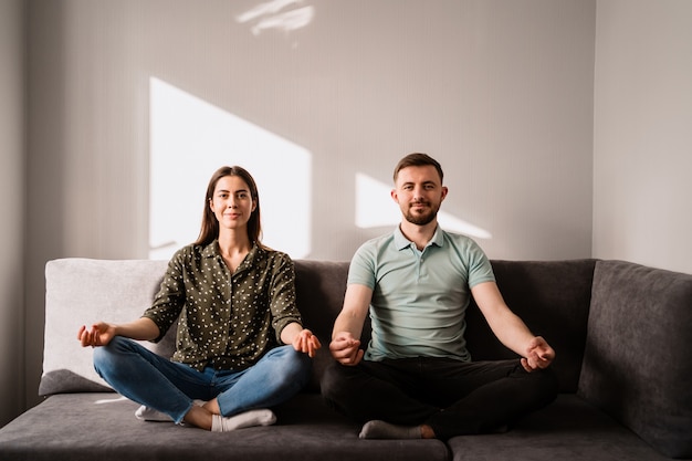 Homem e mulher sentada no sofá em pose de lótus