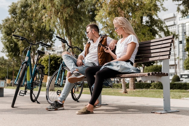 Homem e mulher sentados em um banco ao lado de suas bicicletas