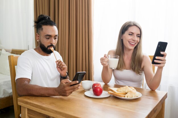 Homem e mulher usando o telefone na cozinha