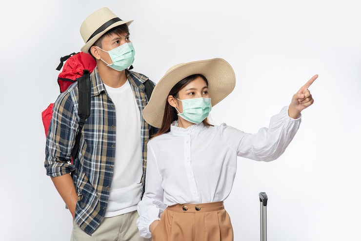 Foto grátis homem e mulher vestidos para viajar, usando máscaras junto com a bagagem