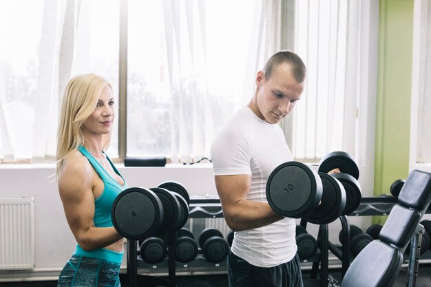 Homem e mulheres levantando dumbbells