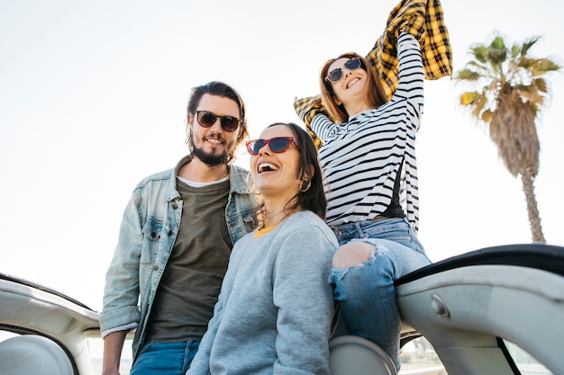 Foto grátis homem, e, mulheres sorridentes, com, mãos erguidas, inclinar-se, de, car