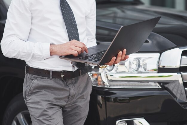 Homem é um homem que trabalha em um laptop e testa dispositivos móveis.