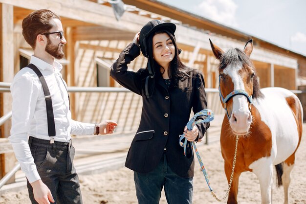 Homem elegante, ao lado de cavalo em uma fazenda com garota