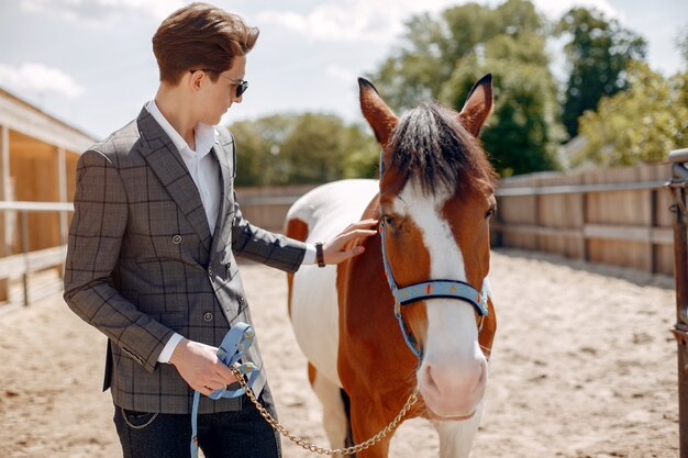 Homem elegante, ao lado de cavalo em uma fazenda