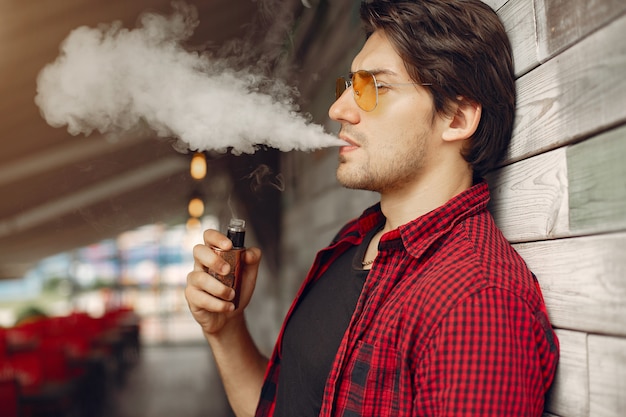 Homem elegante e elegante em uma cidade com vape