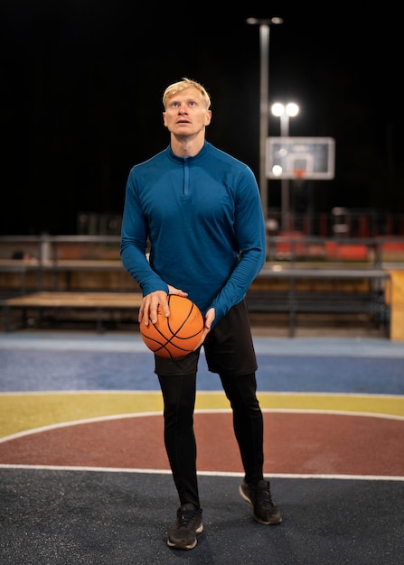 Foto grátis homem em cena, segurando uma bola de basquete ao ar livre