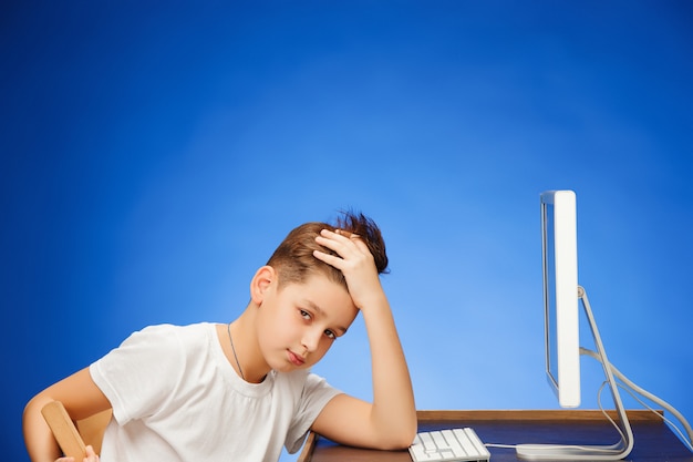 Homem em idade escolar, sentado na frente do monitor de tela