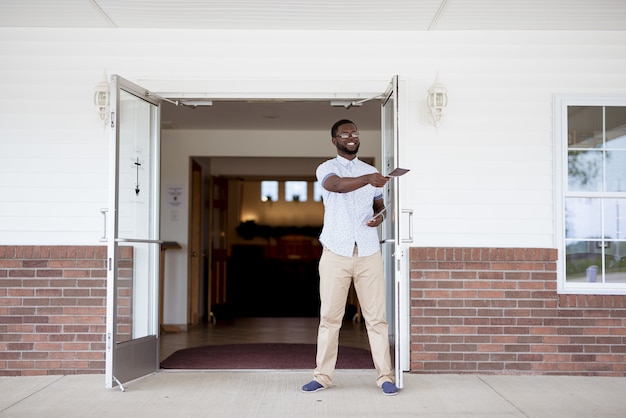 Foto grátis homem em pé perto da igreja distribuindo panfletos