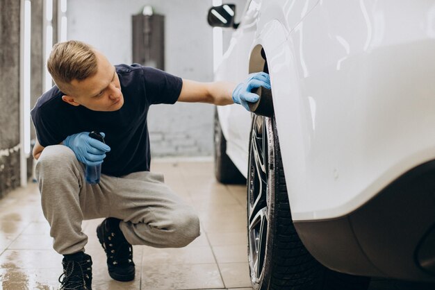 Homem em pneus de polimento limpos de carro